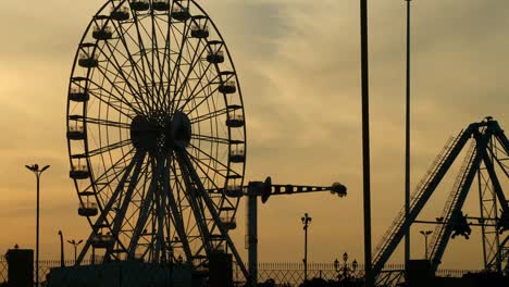 Rueda-De-La-Fortuna-Del-Parque-De-Atracciones-Silueta-Contra-El-Cielo-Naranja-Del-Atardecer