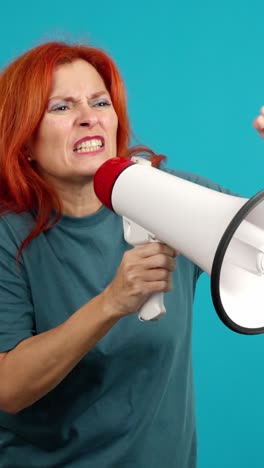 passionate woman with red hair protesting and shouting into a megaphone