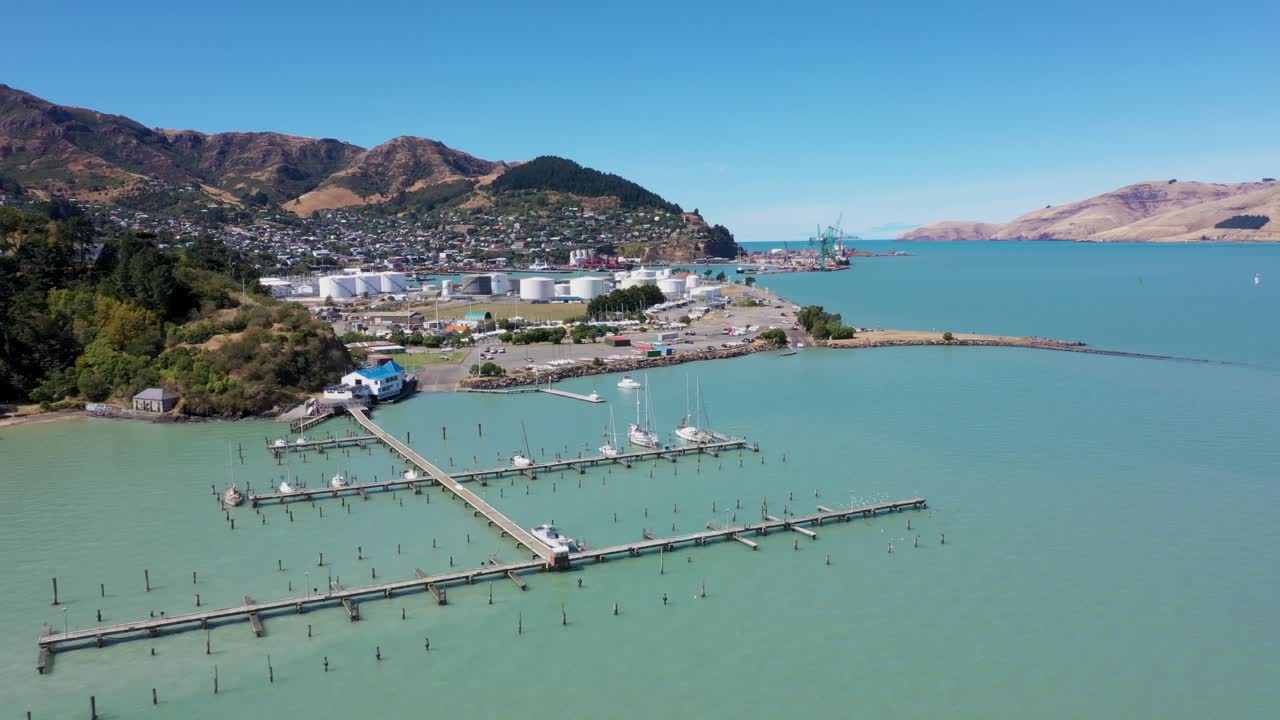 Moving aerial view of port town and harbour with fuel silos
