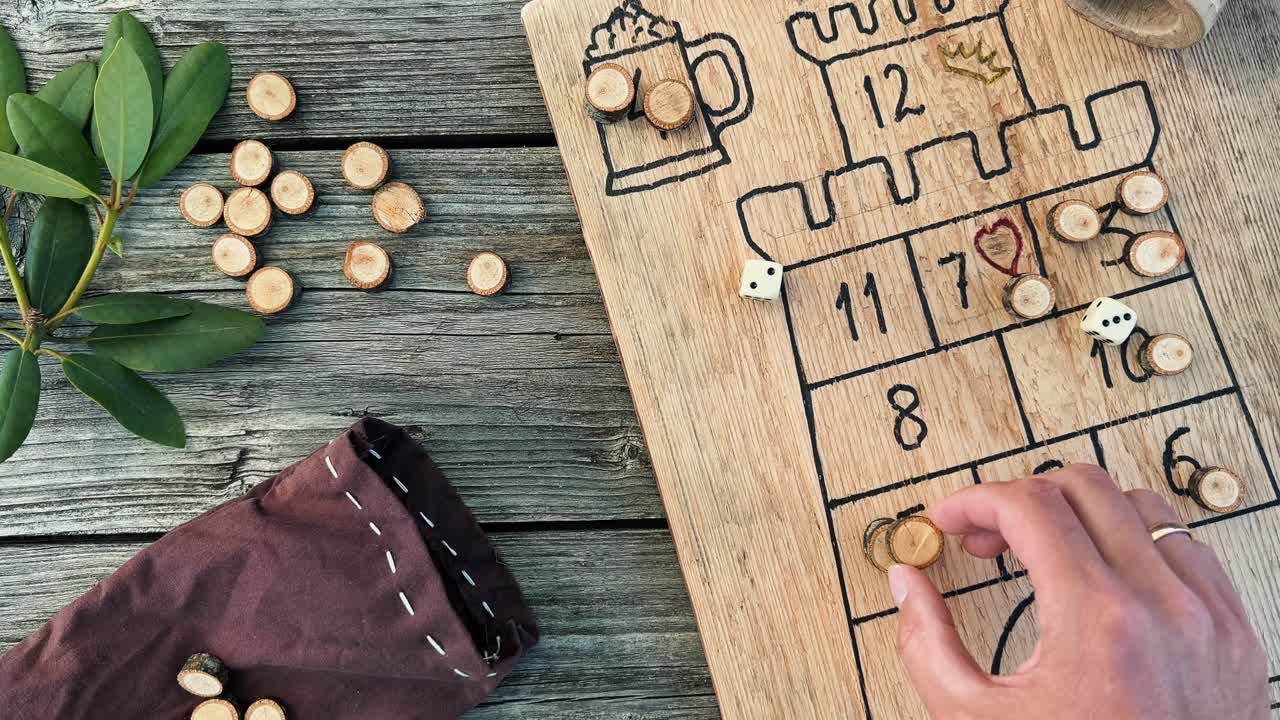 Small wooden pawn on a handmade wooden board game with dice, a dice cup, and a bag of pawns, suggesting a fun and engaging activity