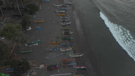 Vista-De-Arriba-Hacia-Abajo-De-Los-Barcos-De-Pesca-En-La-Playa-De-Medewi-Bali-Durante-La-Puesta-De-Sol,-Aérea