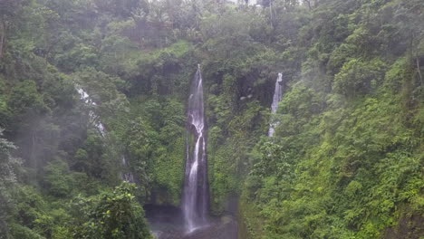 aerial flies through jungle valley mist toward multi cascade waterfall