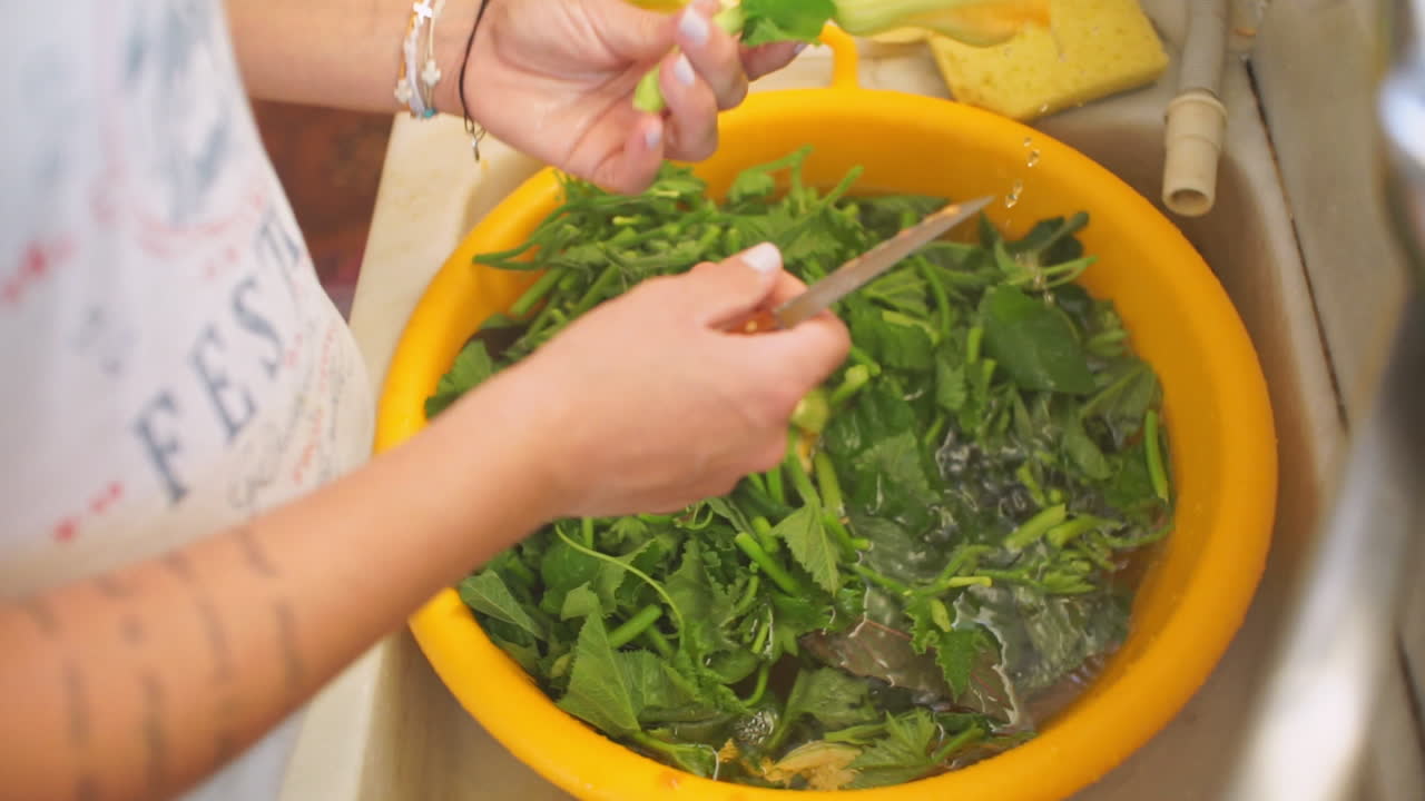 mujer lava verduras en un recipiente de plástico amarillo en casa