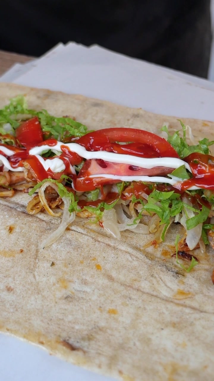 Ajout de ketchup sur un wrap de shawarma au poulet frais
