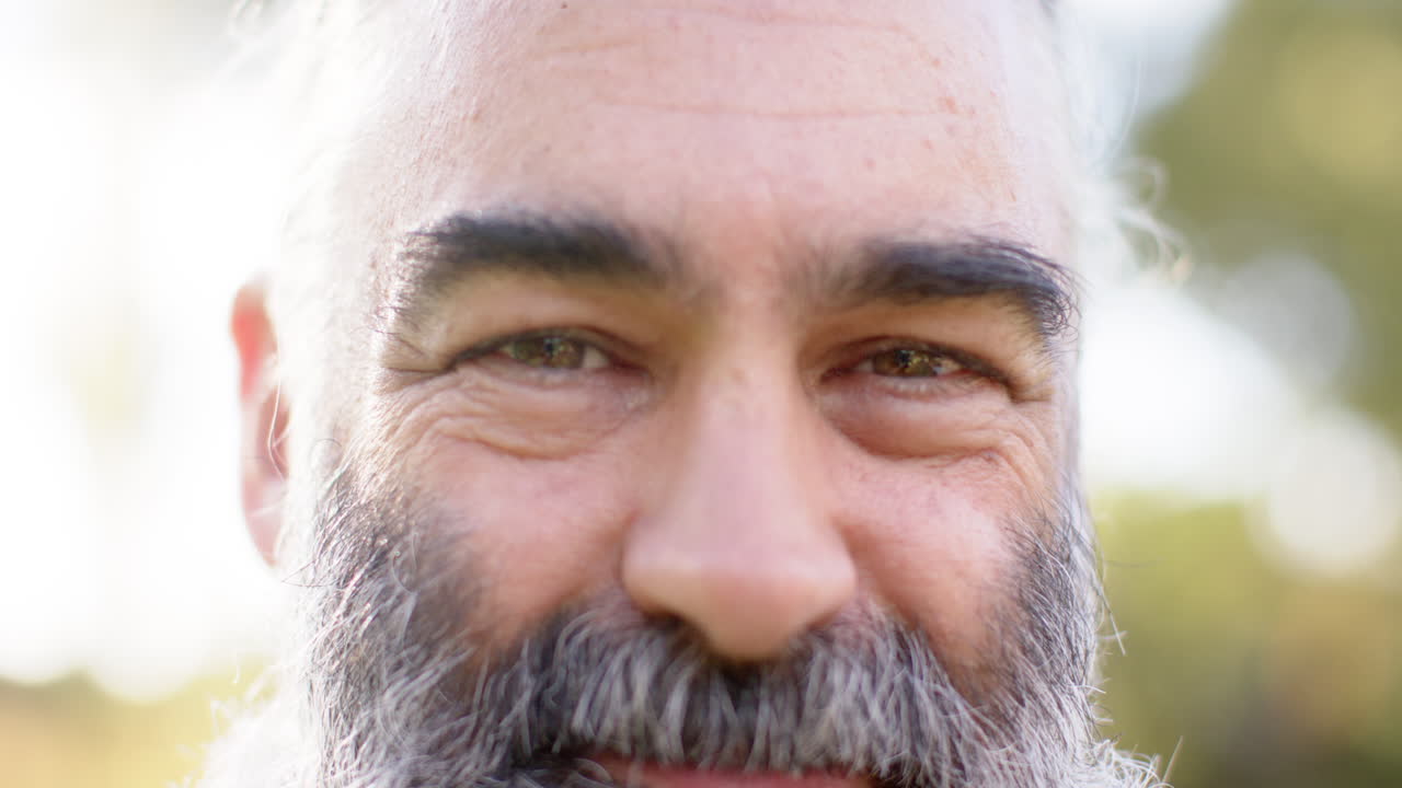Smiling senior man with beard enjoying outdoor time with friends