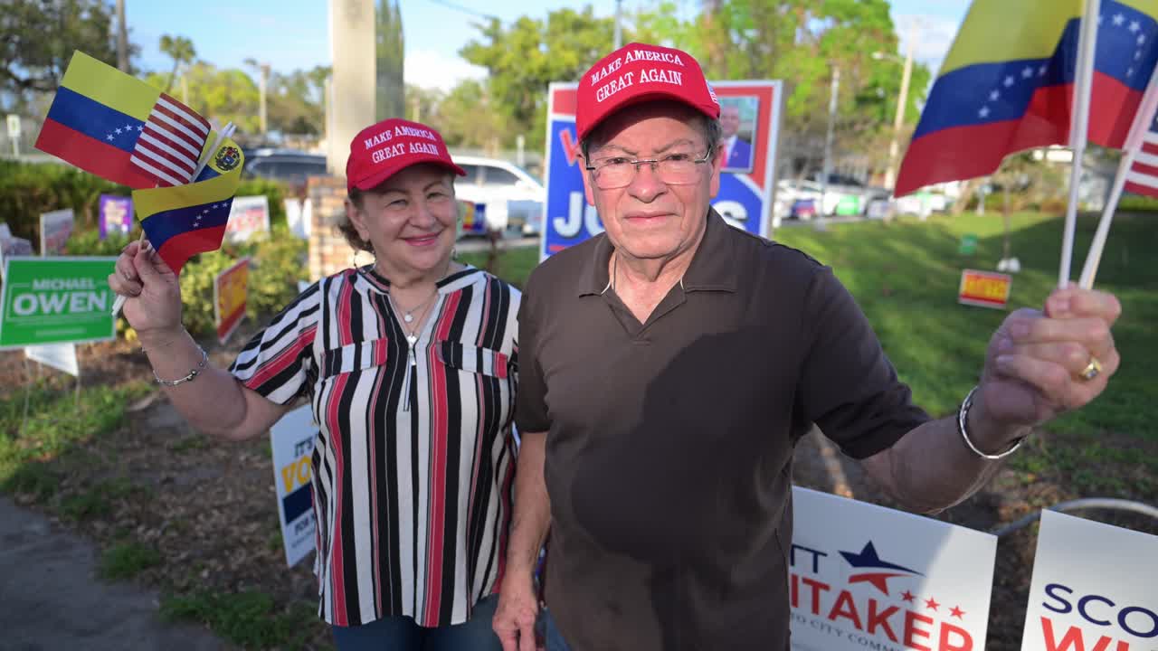 felices votantes de donald trump en el sur de florida agitando las banderas estadounidense y venezolana