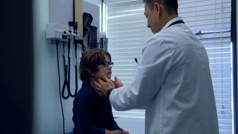 vista lateral de un joven médico asiático examinando a un paciente caucásico en una clínica 4k
