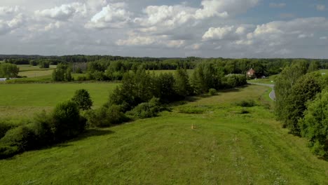 Aerial-footage-over-village-space,-beautiful-green-field,-fresh-grass-and-natural-landscape,-Eastern-Poland,-magical-sky-and-high-trees-on-horizontal