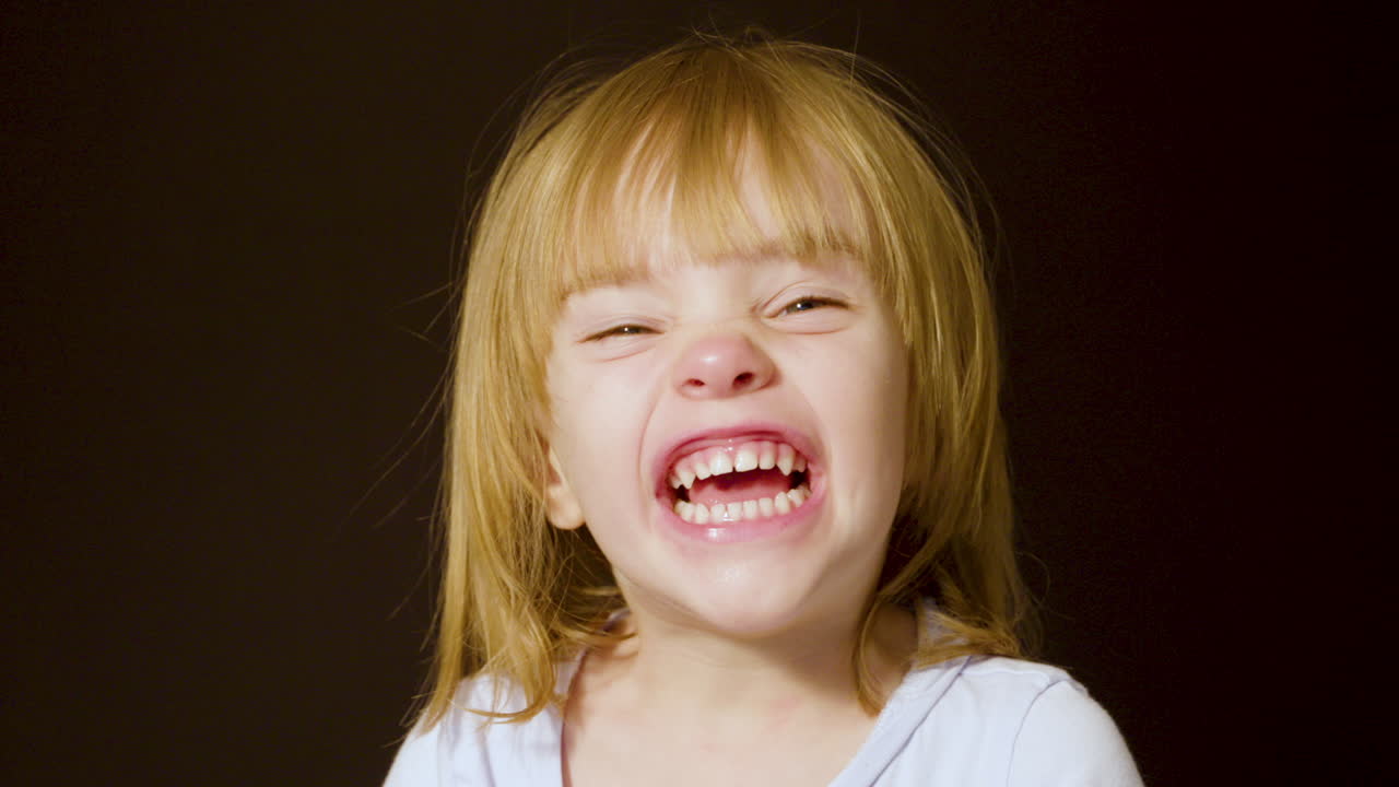 retrato de estudio de una linda niña rubia haciendo caras emocionadas y felices
