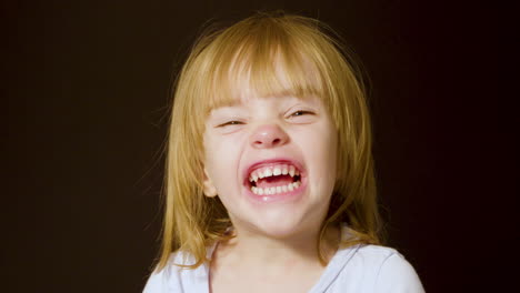 studio portrait of a cute little blonde girl making excited, happy faces