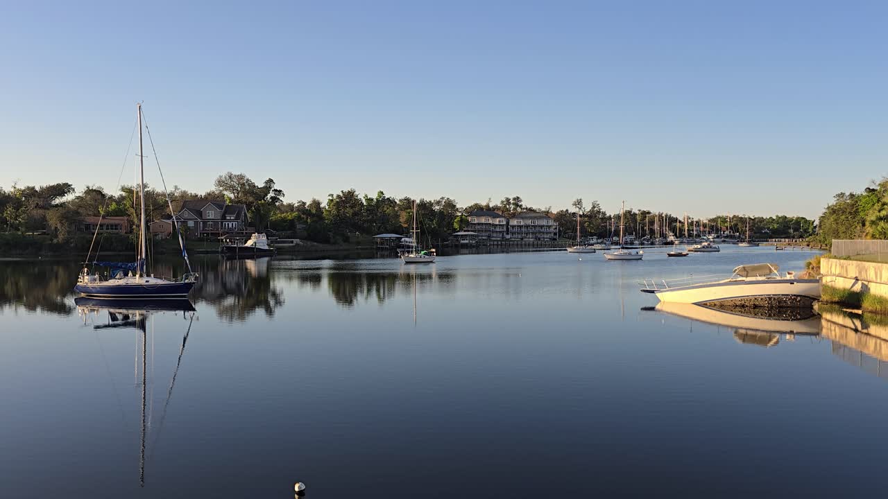 A lovely, clear morning sunrise on the Massalina Bayou in Panama City, Florida. Locals' boats are anchored on the calm waters. A wrecked boat sits among them.