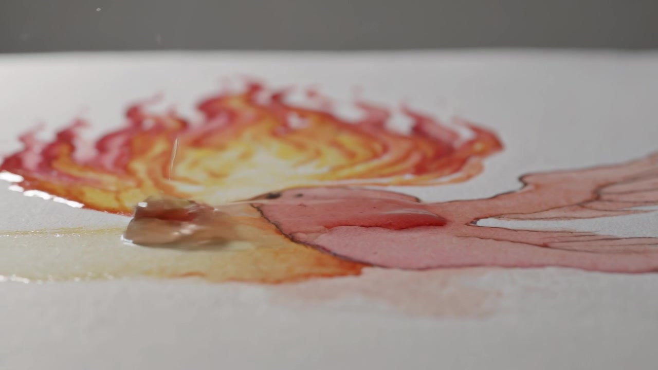 Ugello metallico che rilascia goccioline su un uccello ad acquerello in studio, diluendo pigmenti rosso-arancio.
