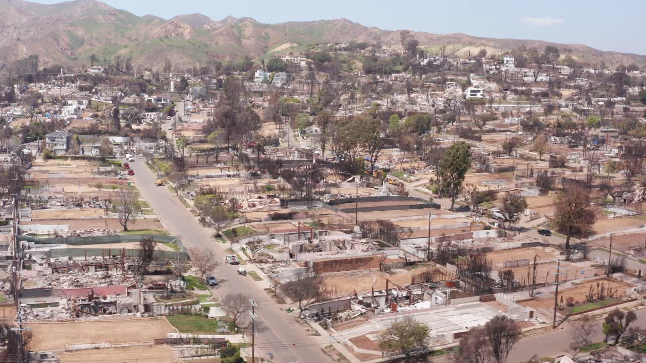 Wide panning aerial shot of a residential neighborhood in Pacific Palisades burned by wildfire in Los Angeles, California. 4K