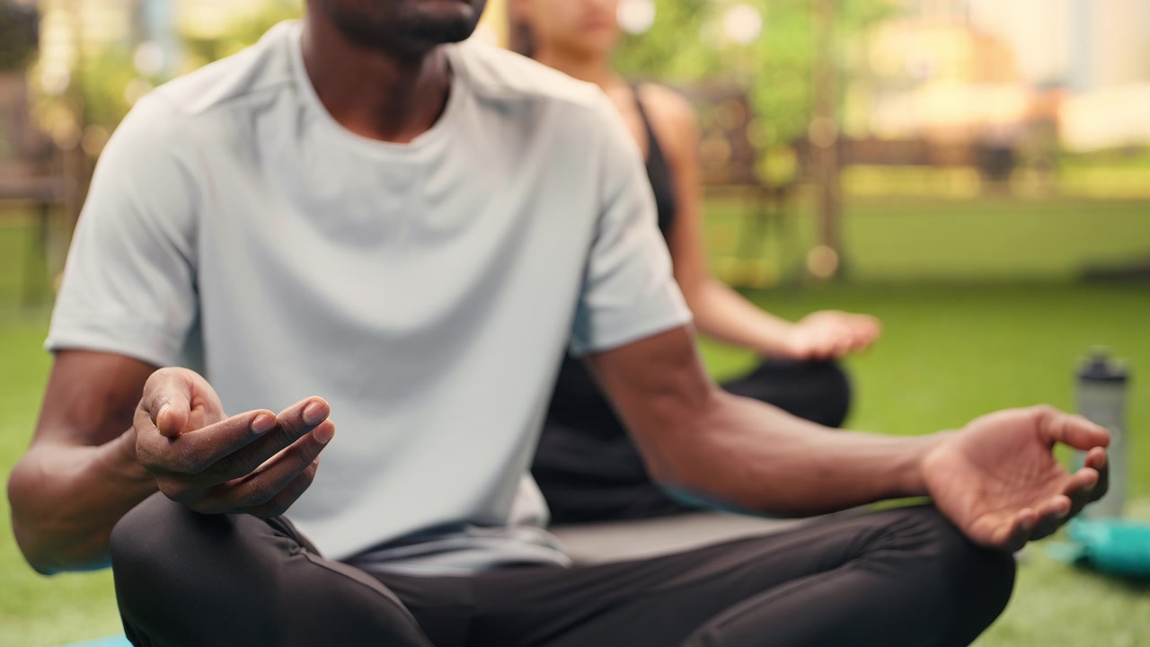 Close-up of man with open hand in meditation gesture while sitting cross-legged
