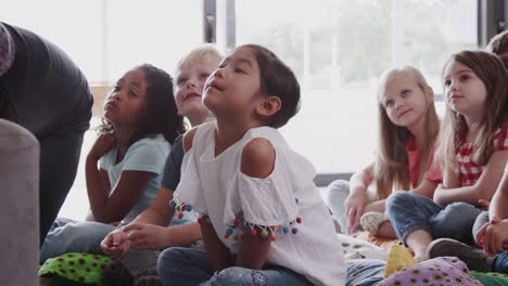 grupo de alumnos de escuela primaria sentados en el suelo escuchando al maestro