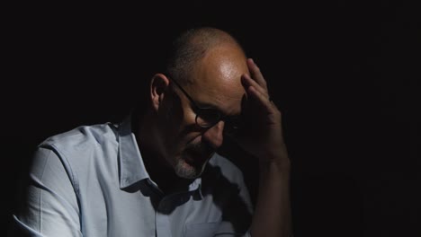 hombre maduro deprimido que lucha con la salud mental sentado en la oscuridad en el sofá con iluminación baja 6