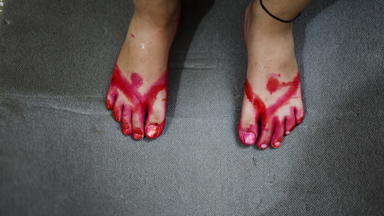 celebración festiva con manos pintando de rojo los pies de un niño