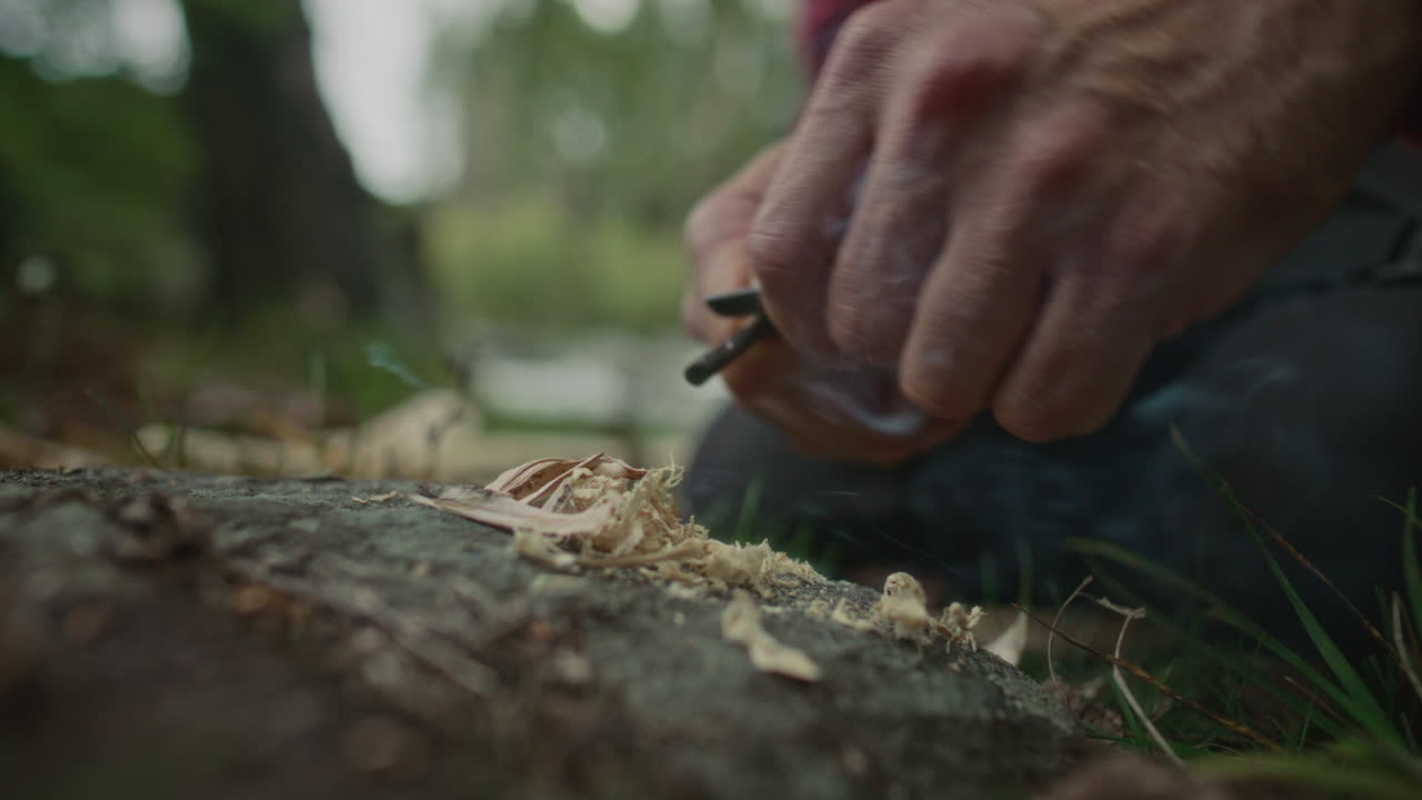 Starting Fire with Ferro Rod over Wooden Feather Stick in Forest