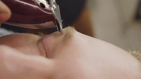 close up of shaving eyebrows with trimmer