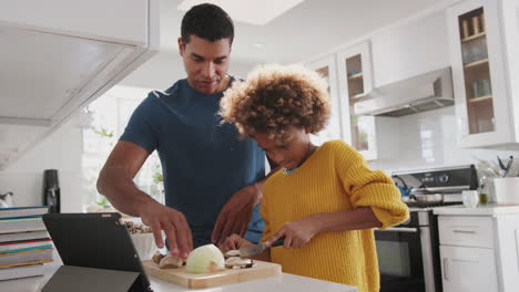 niña preadolescente preparando comida en la cocina con su padre ayudando, de cerca, ángulo bajo