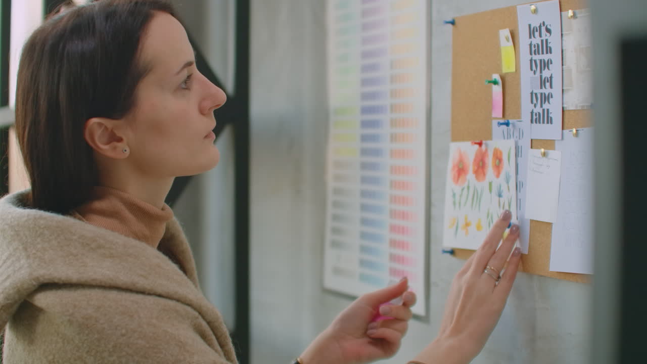 una mujer diseñadora de pie en la pared adjunta sus ideas a la selección de colores de la pared y la colorística. eligiendo un color y preparándose para crear una solución de diseño y color.