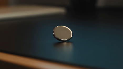 a metallic object spinning on a dark reflective surface