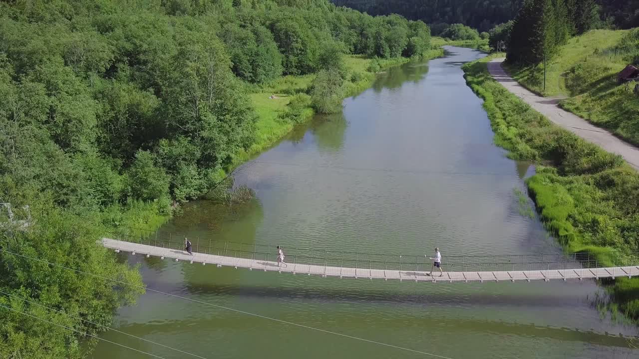 숲 속 의 강 을 가로질러 서스펜션 브릿지 를 가로지르는 사람 들