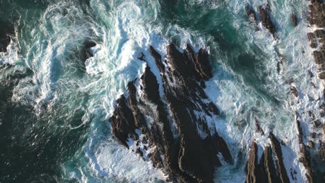 ocean waves on rocky coast, top down aerial drone view of rough sea water surface