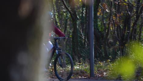ciclismo a través de árboles en el sendero del parque, chica de bicicleta de montaña con casco, día soleado de invierno paseo alegre