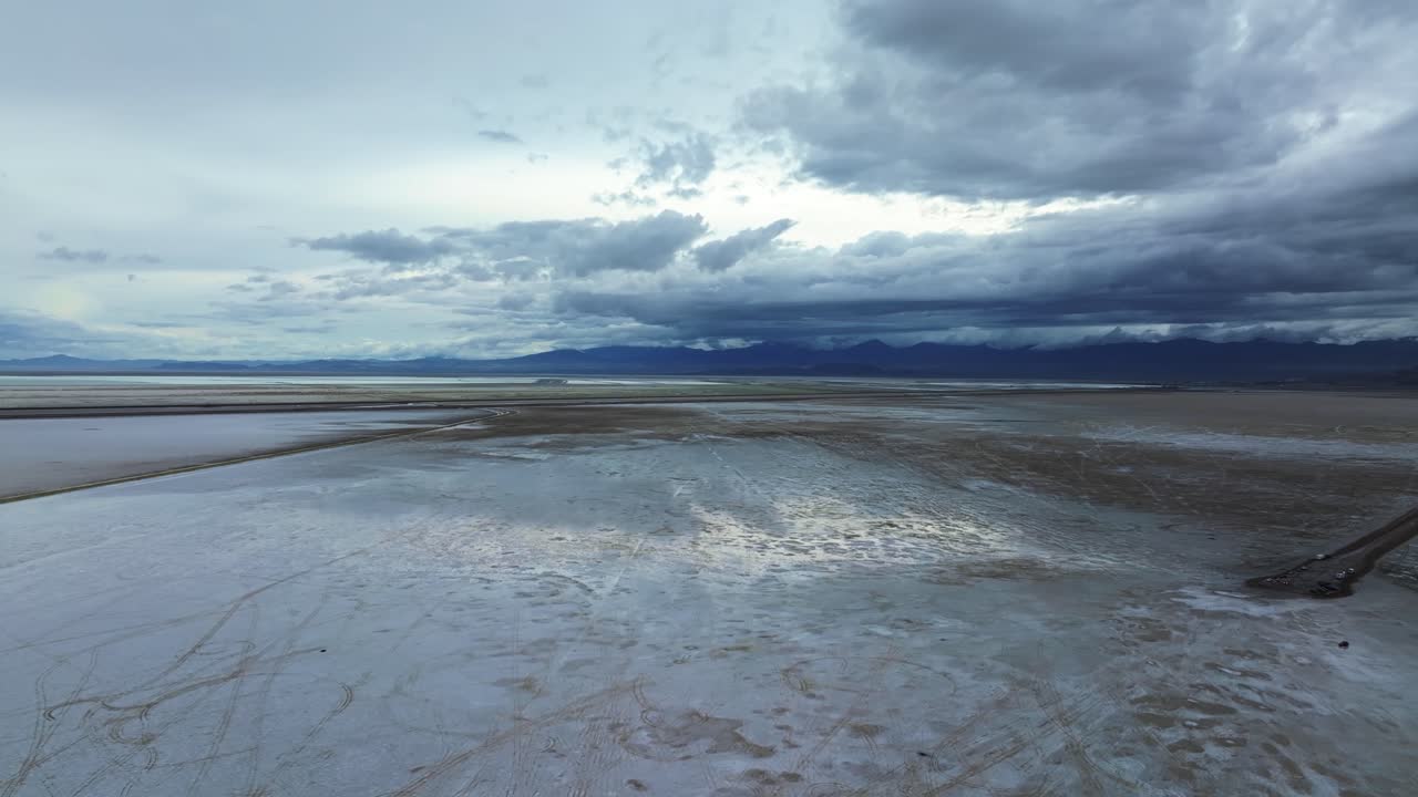 Extreme wide aerial drone left trucking shot of the tourist destination Bonneville Salt Flats in Utah near Wendover Nevada on a stormy spring evening with patches of wet and dry spots from rain
