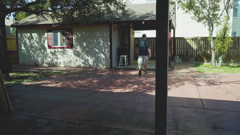 wide shot of a man walking towards the backyard tool shed