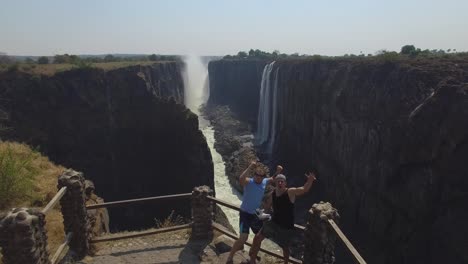 drone shot of happy people celebrating at the viewpoint of victoria falls from zambia, during dry season