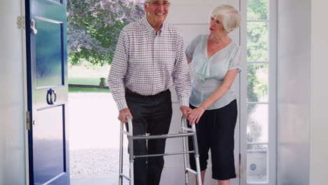 Senior-couple-at-home-talking,-man-using-a-walking-frame