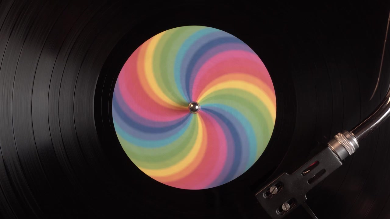 Disco de vinilo con pegatina de ilusión óptica de arcoíris girando en tocadiscos, vista cenital.