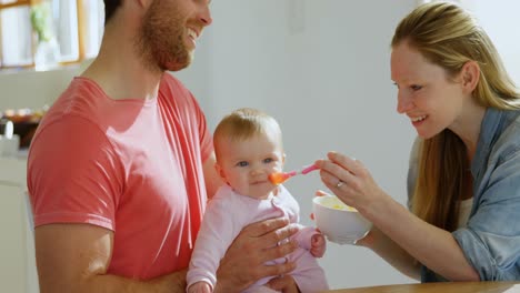 padres alimentando a su bebé en casa 4k