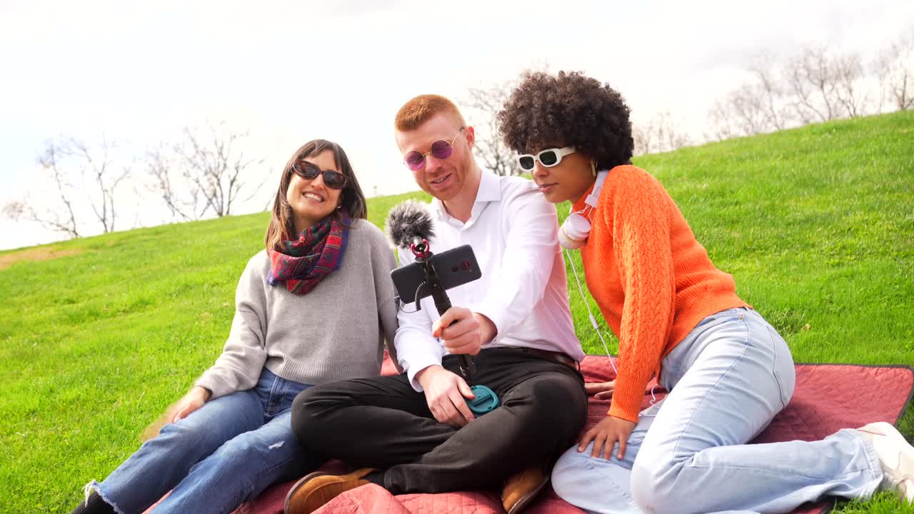 Friends recording video blog on grass