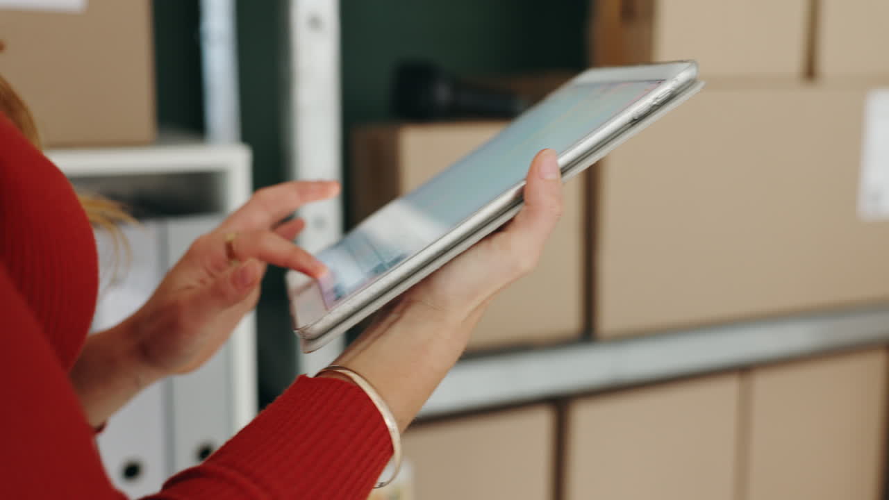 Woman using tablet in warehouse with boxes