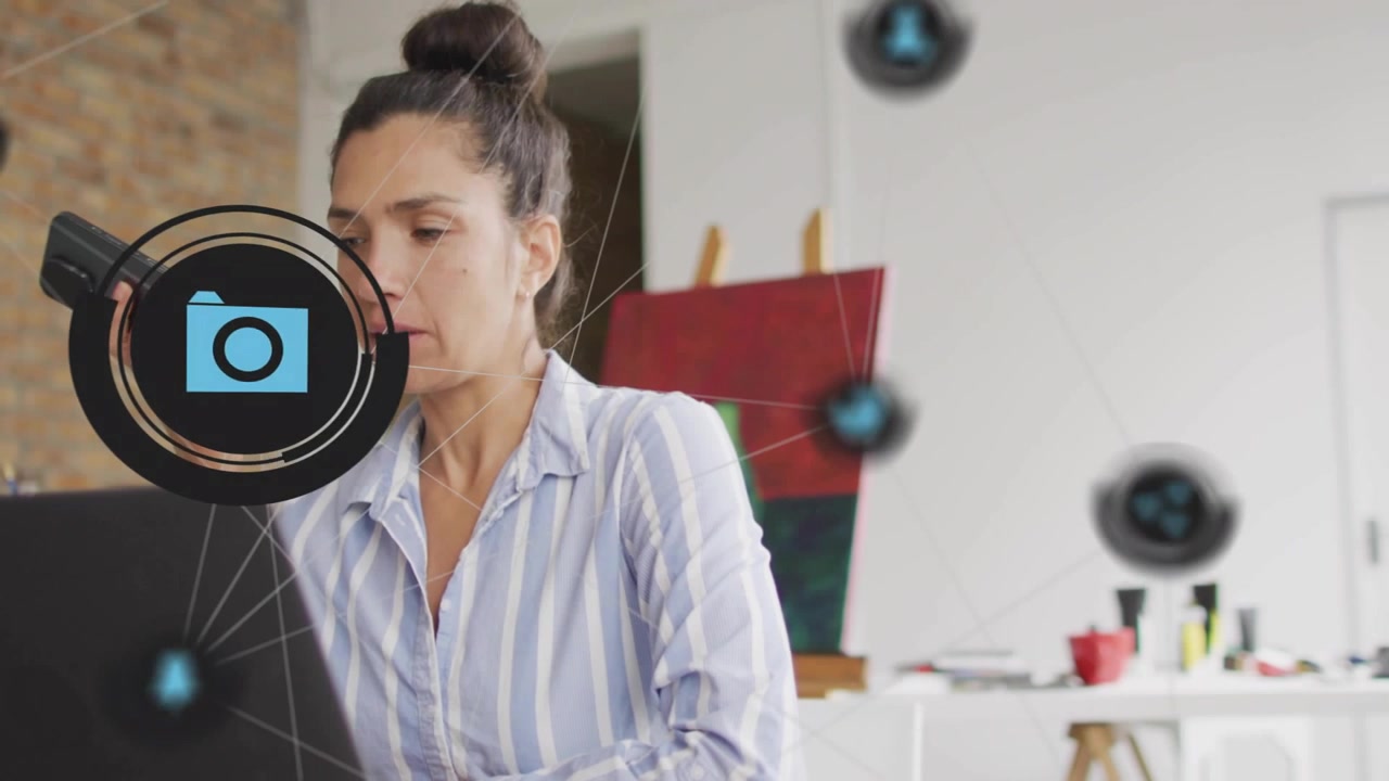 Mulher falando ao telefone em uma mesa de estúdio, com ícones flutuantes de redes sociais pulsando ao redor de um laptop.