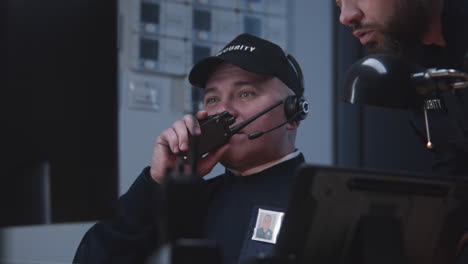 security guards working in a control room, communicating with a walkie-talkie