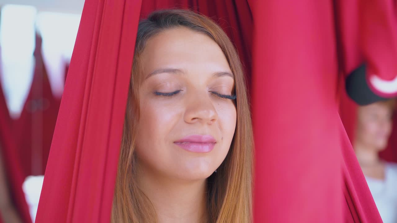 una mujer con piel perfecta se sienta en una hamaca de yoga anti-gravedad
