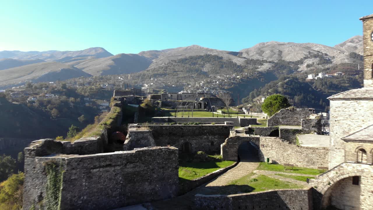 Torre dell'orologio della splendida cittadella ad Argirocastro con alte mura in pietra costruite su una collina con prati verdi