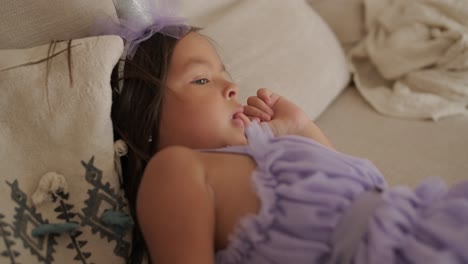 una niña con un vestido está viendo la televisión en el sofá de la sala de estar