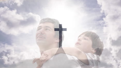 animation of crucifix cross monument and cloudy sky over caucasian father carrying son