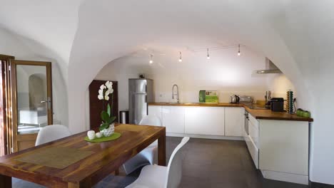 slow orbiting shot revealing a modern white kitchen and dining area with patio doors