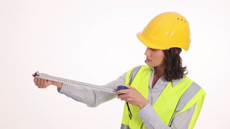 woman in hard hat and safety vest using a measuring tape