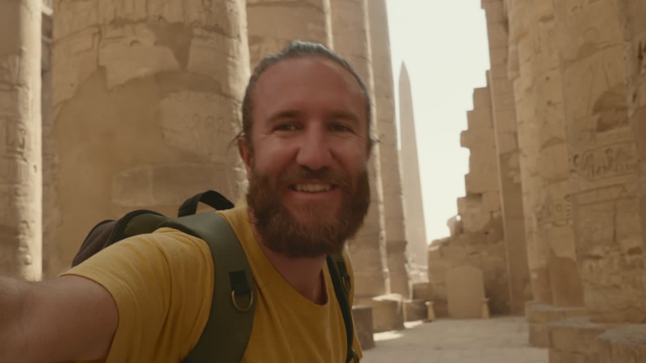 럭소르의 고대 이집트 사원을 둘러보는 젊은 남자가 멋진 셀피를 찍습니다.