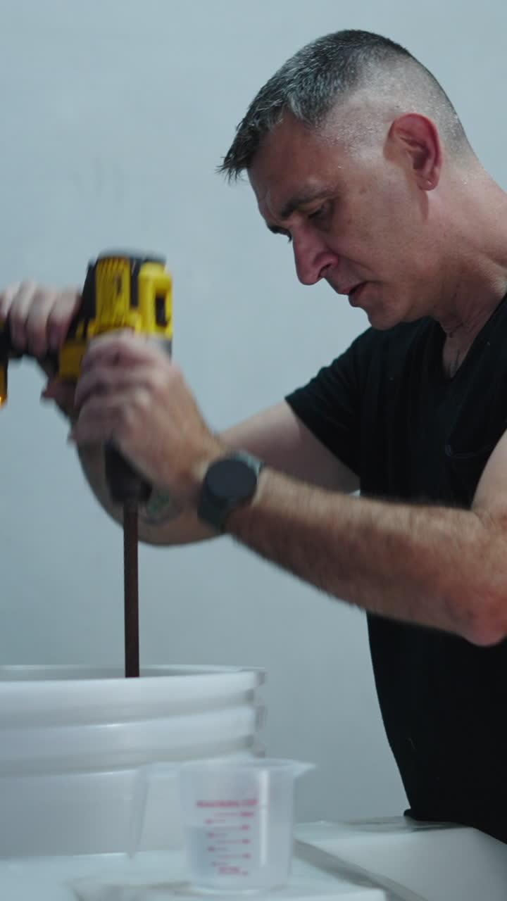 Man Mixing Material in a Bucket with a Power Drill