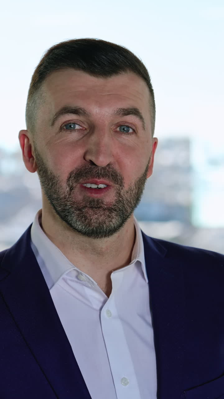 Smiling bearded professional businessman looking at camera. Confident handsome adult entrepreneur speaking in office. Face view business portrait close up. Vertical video