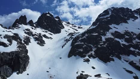 gente haciendo freeride por la ladera rocosa de una montaña nevada