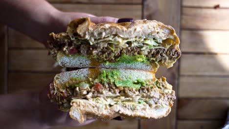 a close up of a nyc bodega style chopped cheese sandwich being pulled apart in slow motion by hands with a perfect manicure to reveal the fillings